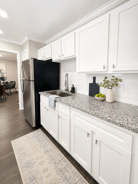A kitchen with white cabinets and a black fridge.