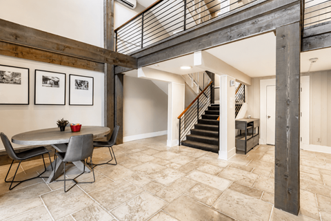 A dining room with a table and chairs and a staircase.