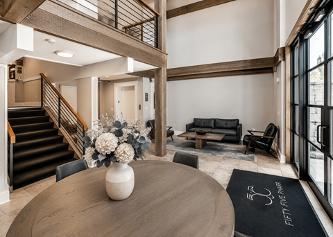 A living room with a wooden table and a vase of flowers.