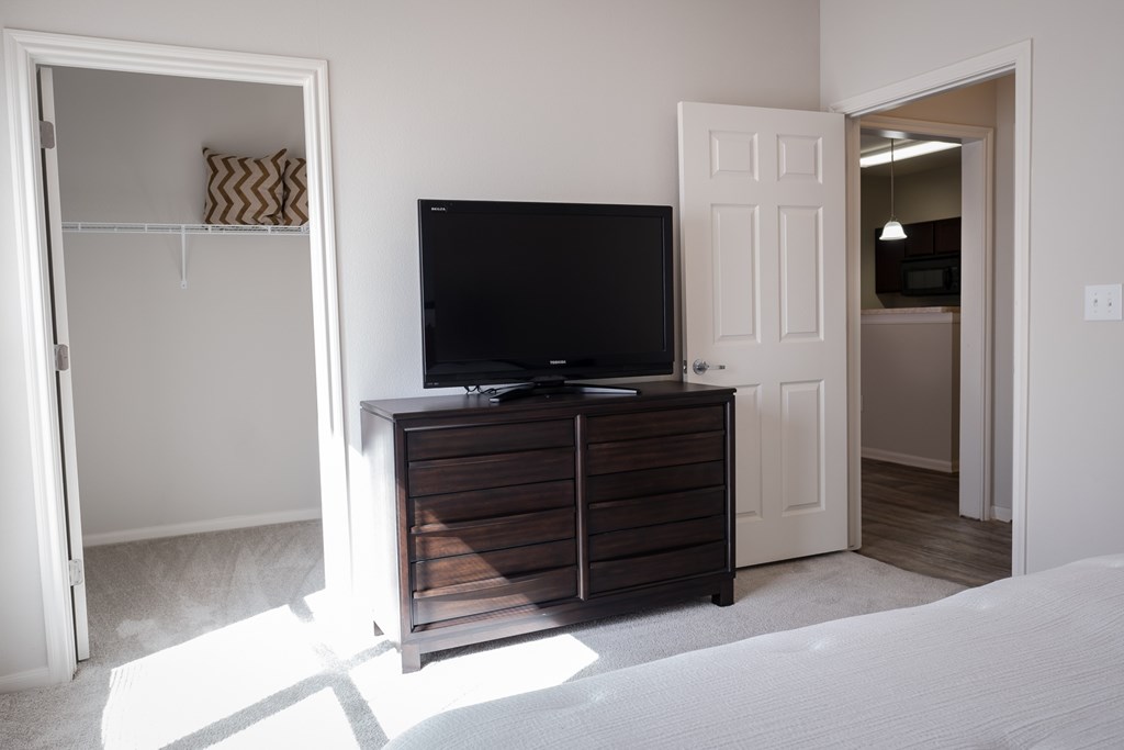 A black TV sits on a wooden cabinet in a room with white walls.