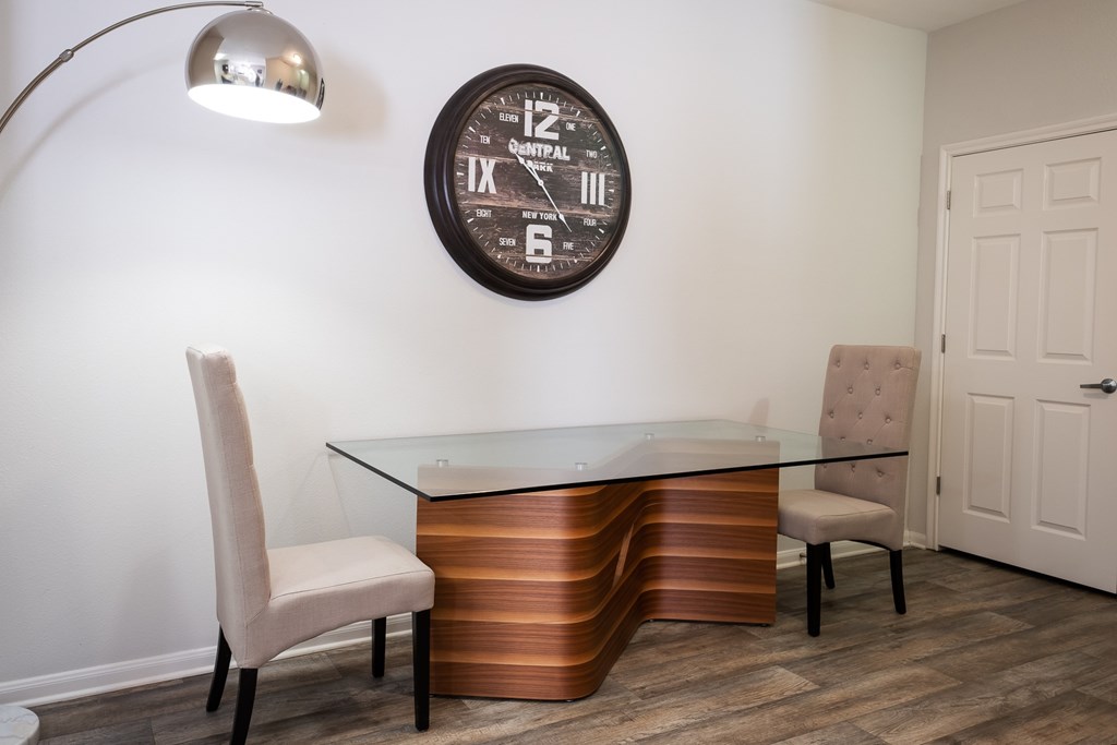 A modern room with a glass table and a clock on the wall.