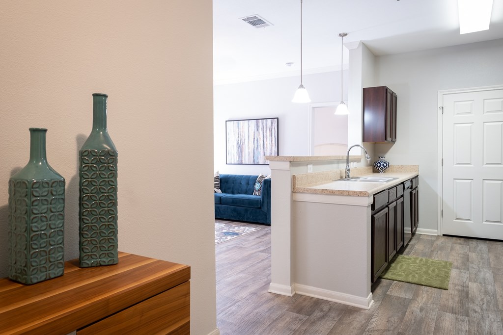 Two green bottles on a wooden table in a room with a blue couch.