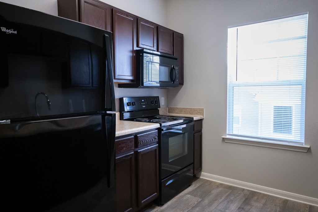 A kitchen with black appliances and brown cabinets.