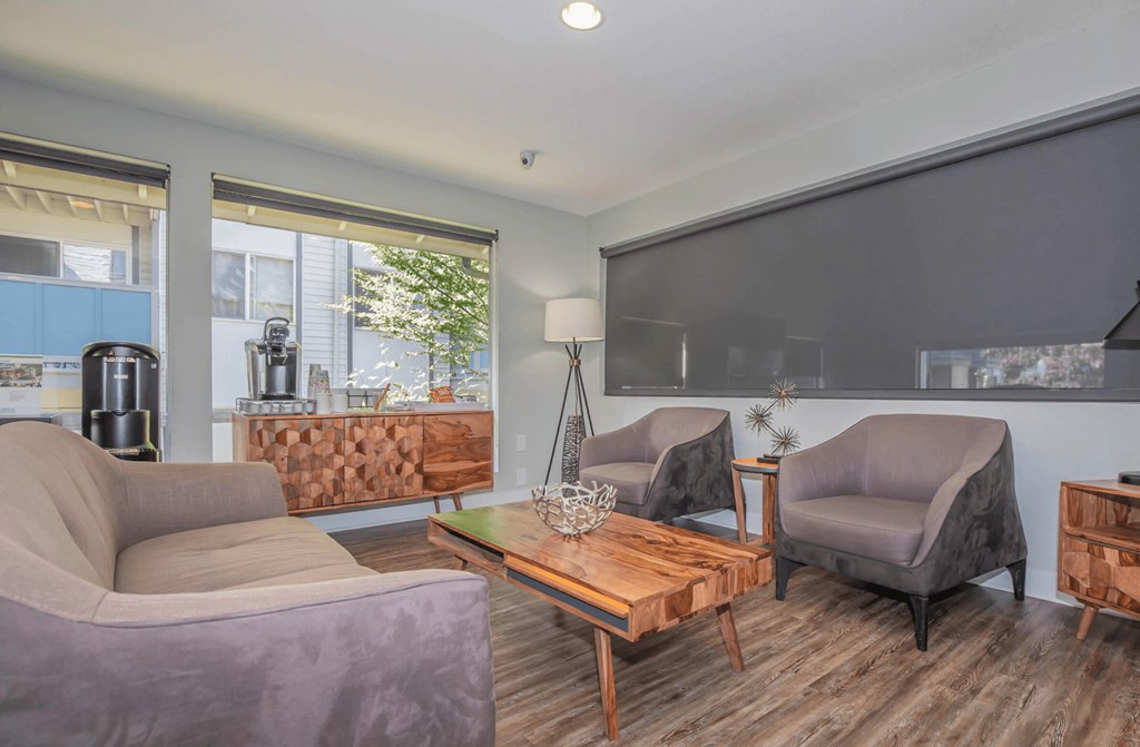 Inside the renovated leasing office at Foster Creek apartments with gray couches and chairs and a wooden coffee table