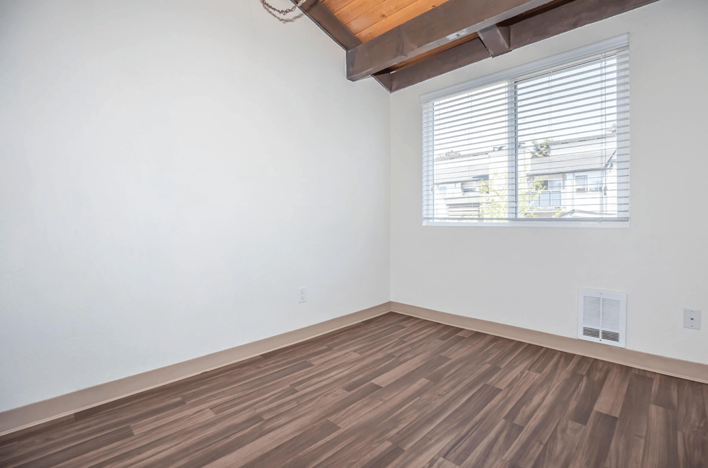 Interior room with hardwood floors, vaulted ceiling and a window and white walls at Foster Creek apartments