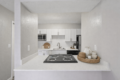 A kitchen with white cabinets and a black stove top.