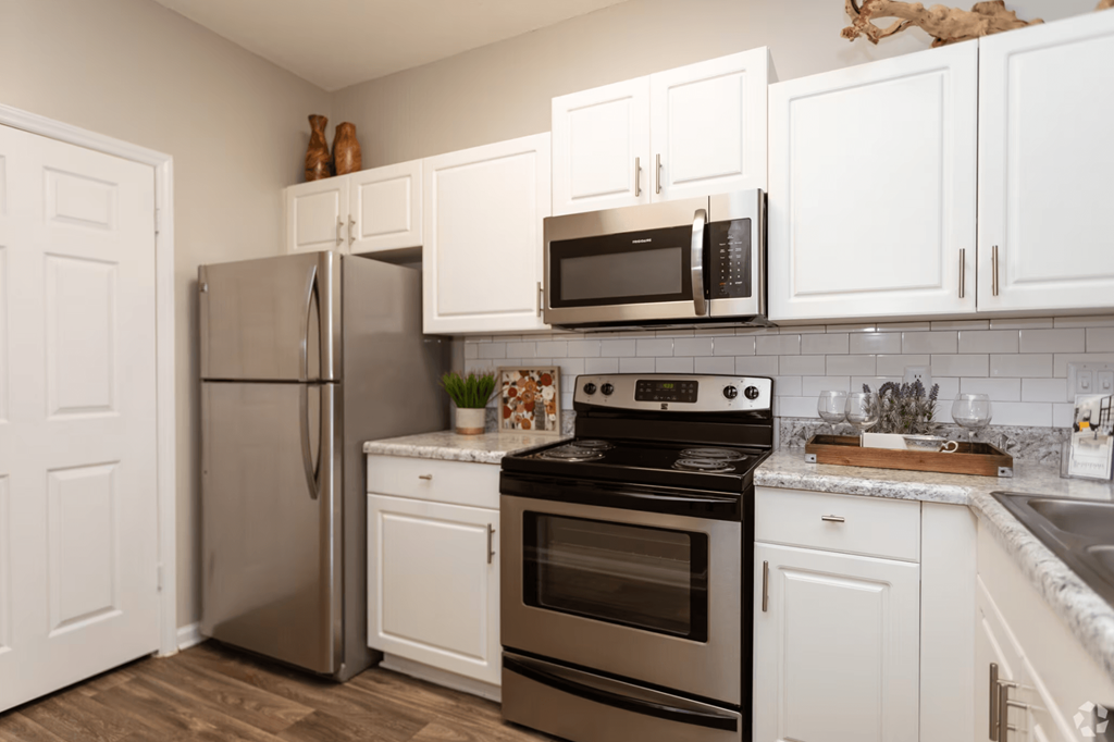 A kitchen with a stainless steel refrigerator, oven, and microwave.