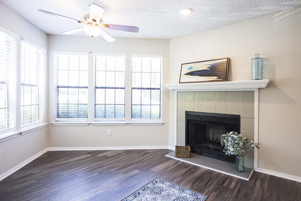 an empty living room with a fireplace and windows