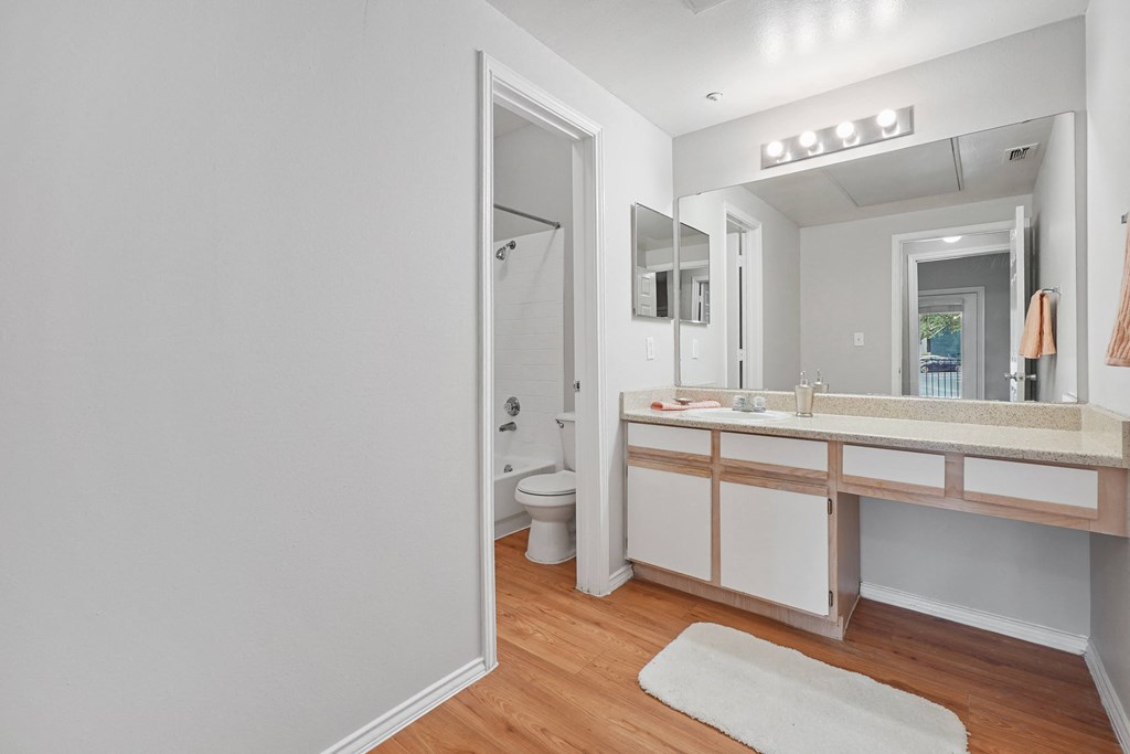 a bathroom with white walls and wood flooring