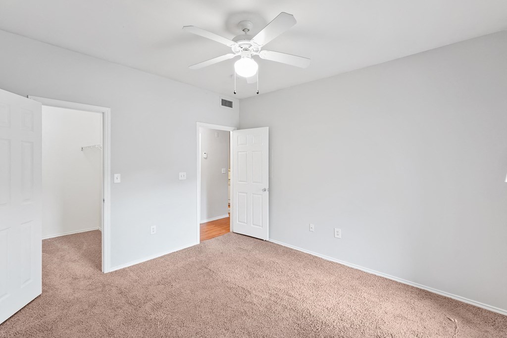 a bedroom with gray carpet and a white ceiling fan