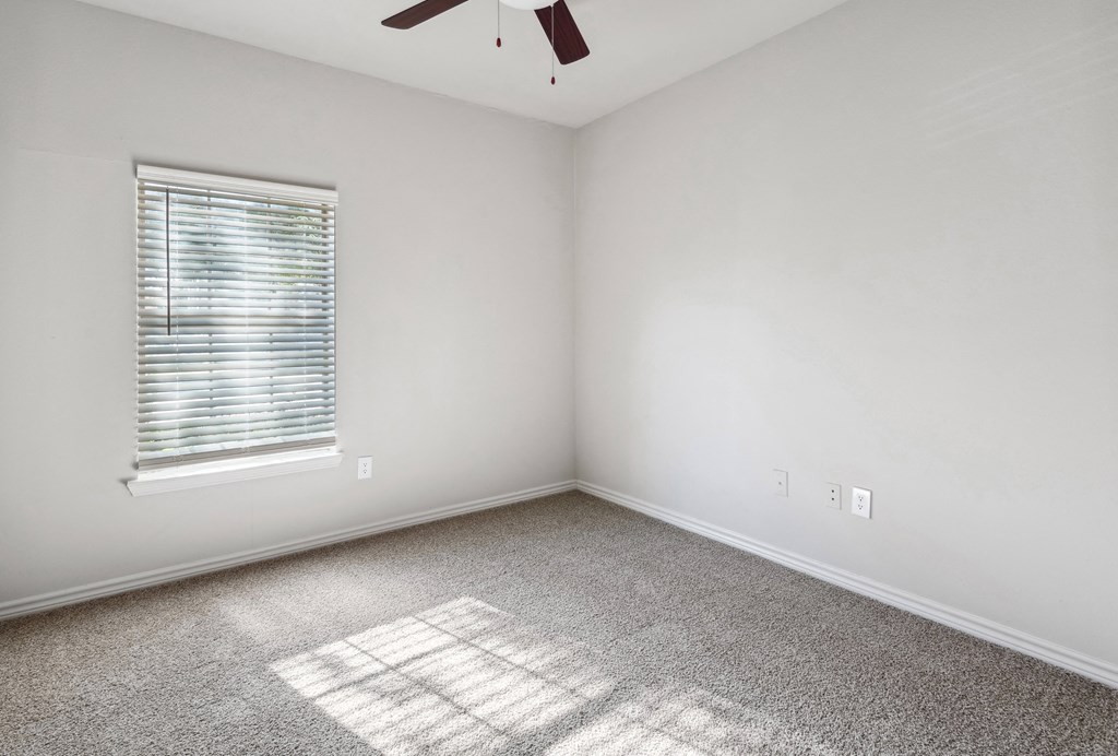 an empty room with a window and a ceiling fan