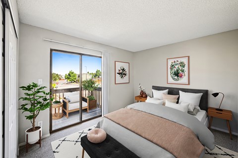 A bedroom with a large bed and a view of a balcony with furniture.