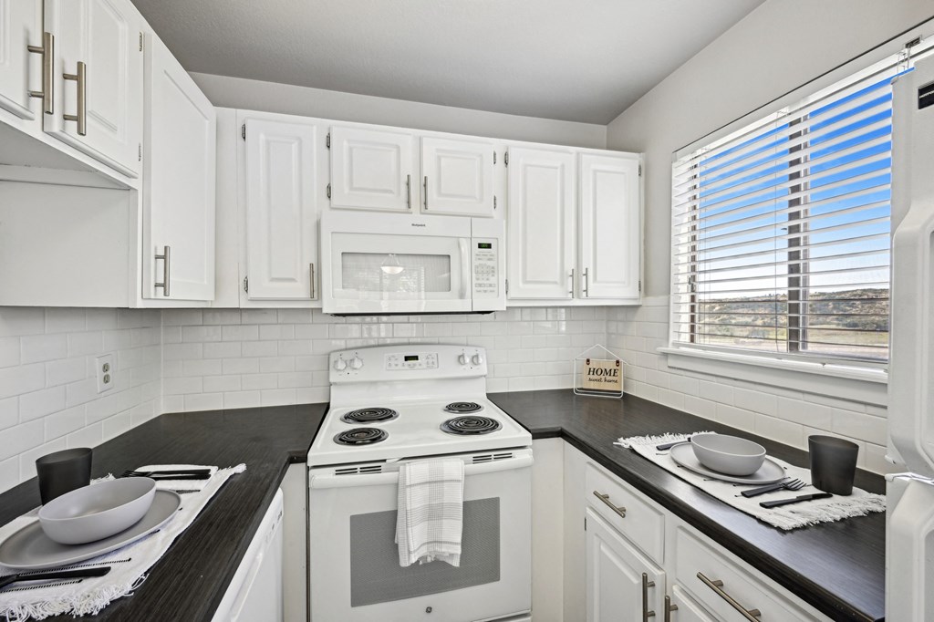an empty kitchen with white cabinets and appliances