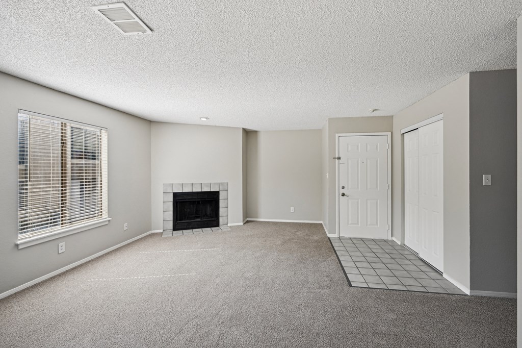 an empty living room with a fireplace and a white door