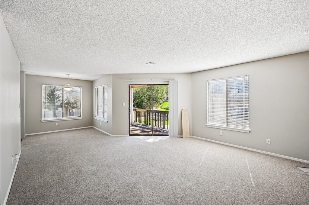 an empty living room with a door to a balcony