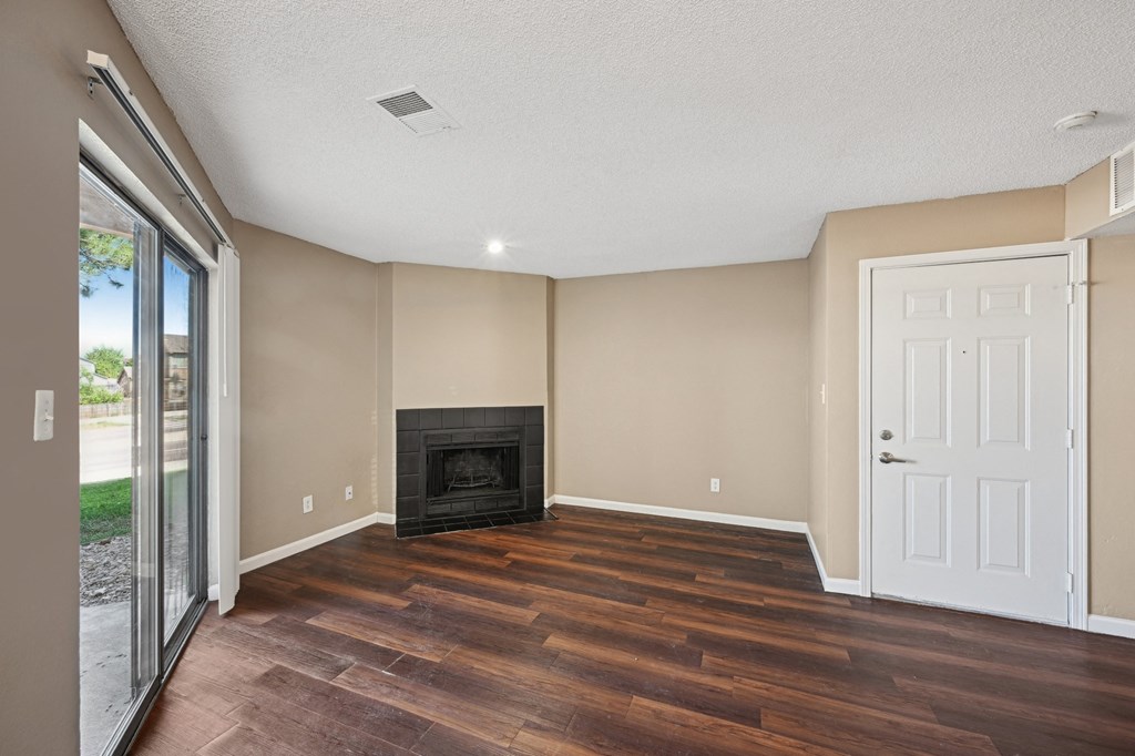 an empty living room with wood floors and a fireplace