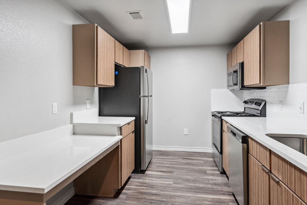 an empty kitchen with white countertops and a stainless steel refrigerator