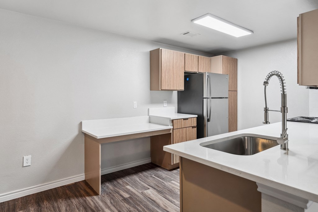 an empty kitchen with white countertops and a stainless steel refrigerator
