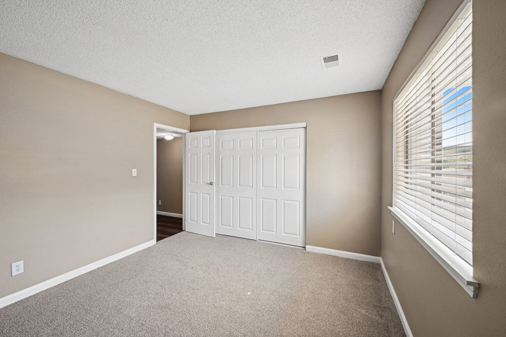 an empty living room with a large window and a white door