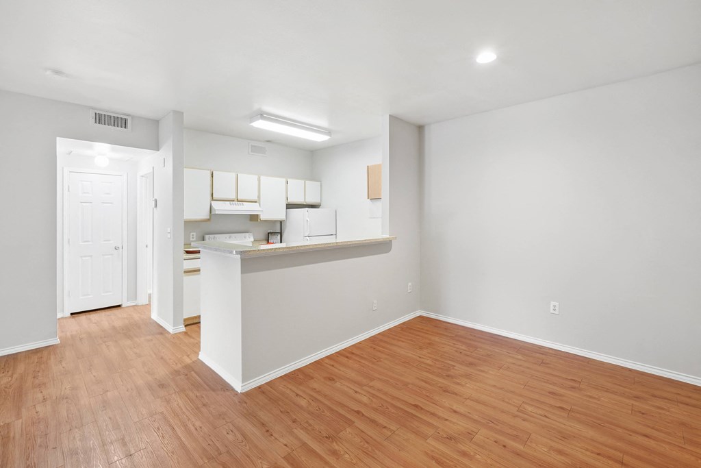 a bedroom with a medium hardwood floor and a kitchen in the background