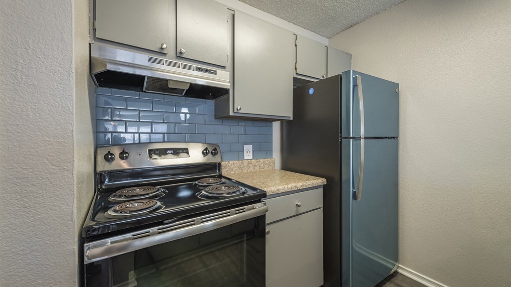 1 Bedroom Apartments in Duluth, GA - The Eclipse - Kitchen with Stainless Steel Appliances, Granite Countertops, Light Grey Cabinetry, Tile Backsplash, and Designer Wood Look Plank Flooring