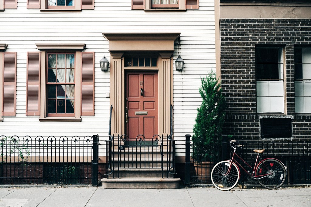 a bike parked in front of a white house with a red door