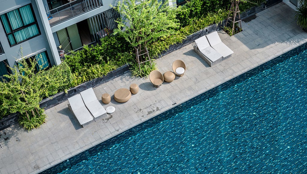 a hotel pool with chairs and umbrellas next to a swimming pool
