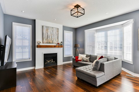 A living room with a grey couch and a fireplace.