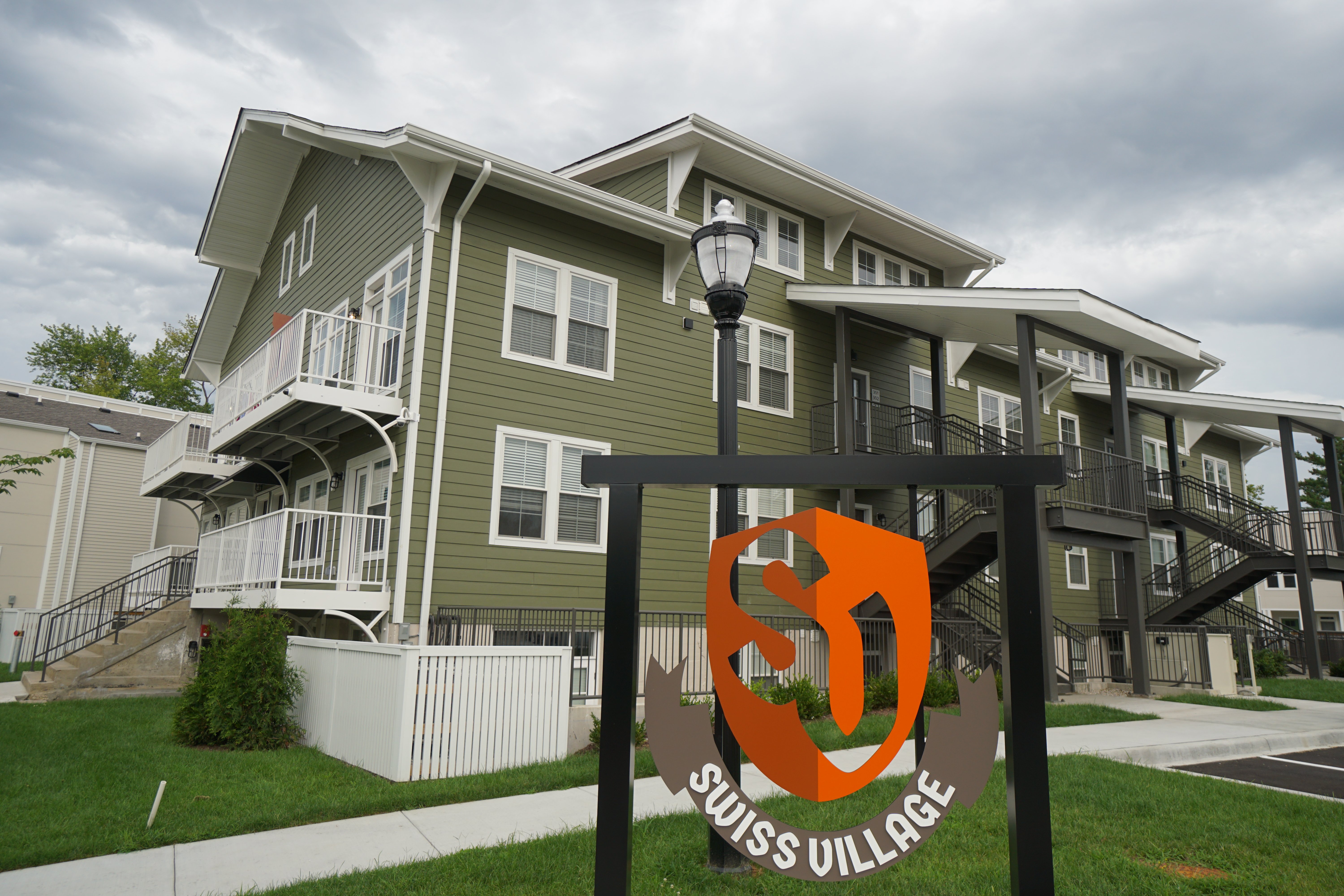 A sign for Swiss Village stands in front of apartment buildings.