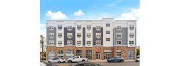A multi-story apartment building with cars parked in front.