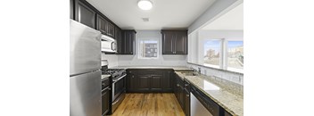 A kitchen with black cabinets and a stainless steel refrigerator.
