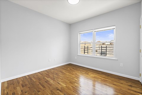 A room with wooden floors and a window overlooking a cityscape.