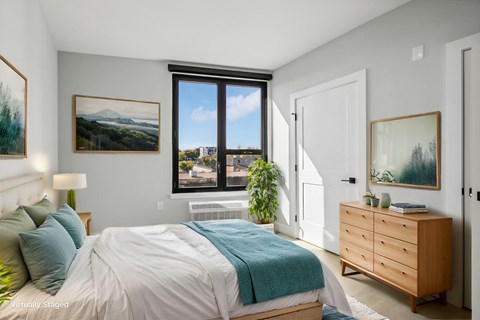 A bedroom with a bed, dresser, and a window with a view of the outdoors.