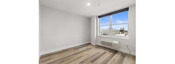 A room with a window and a wall-mounted air conditioner.