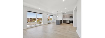 A spacious, well-lit room with a kitchen area and a view of the outdoors through large windows.