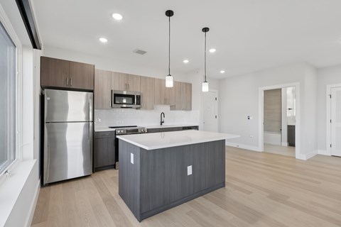A modern kitchen with a stainless steel refrigerator and wooden cabinets.