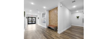 A hallway with a wooden floor and a patterned wallpapered wall.