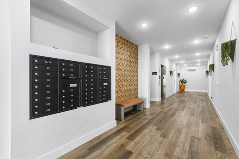 a long hallway with white walls and wood floors and a locker on the wall