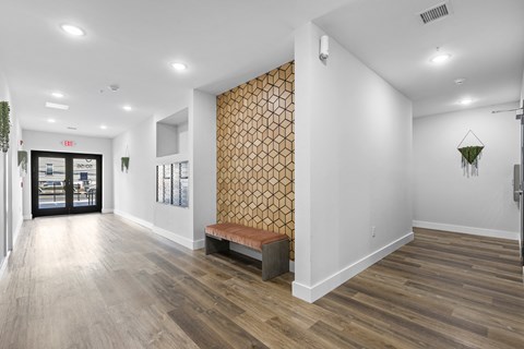 a hallway with white walls and wood floors and a bench