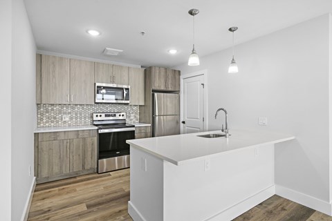 A kitchen with a white countertop and wooden cabinets.