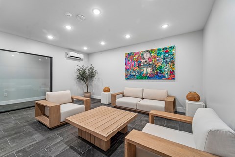 A modern living room with a large painting on the wall and comfortable seating.