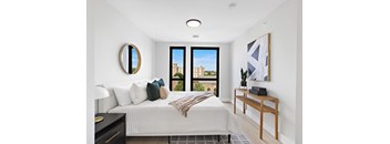 a bedroom with a large bed and a wooden desk with a potted plant