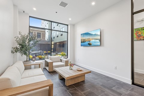 A living room with a white couch and a painting of a lake on the wall.