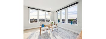 A living room with a white chair and a blue rug.
