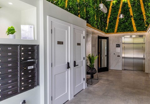 a hallway with white doors and a green wall covered in plants