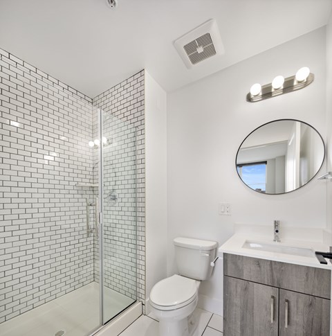 A white toilet sits next to a sink in a bathroom with a glass shower stall.