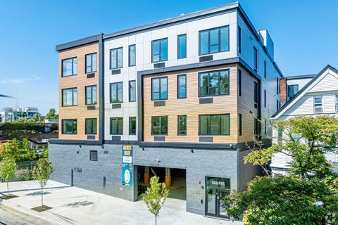 A modern multi-story building with a parking lot in front.