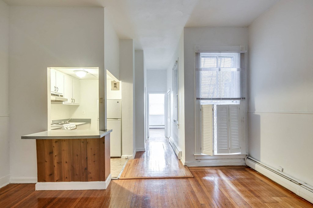an empty room with a kitchen and a door to a hallway
