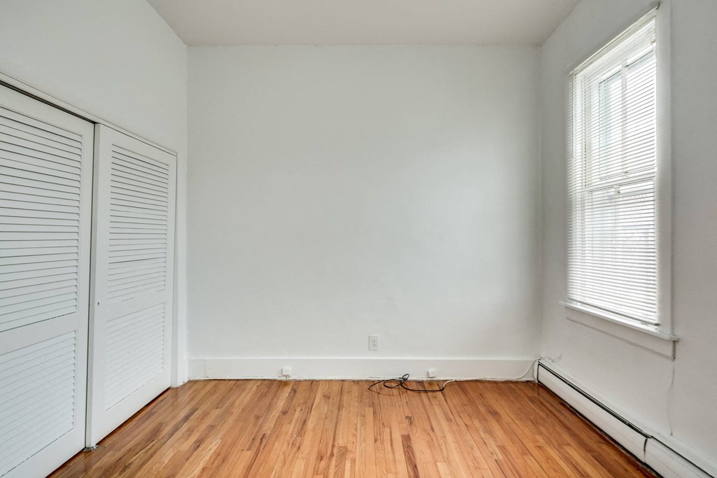 an empty room with wood floors and white walls