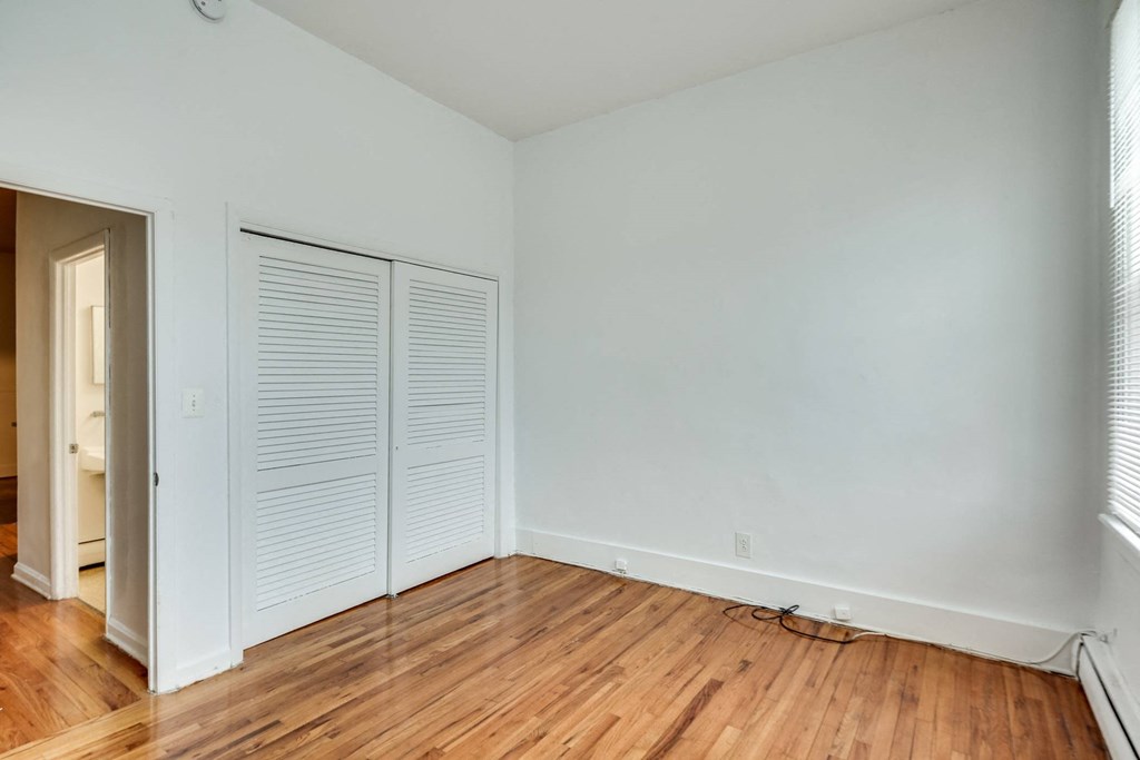 an empty room with wood floors and white walls